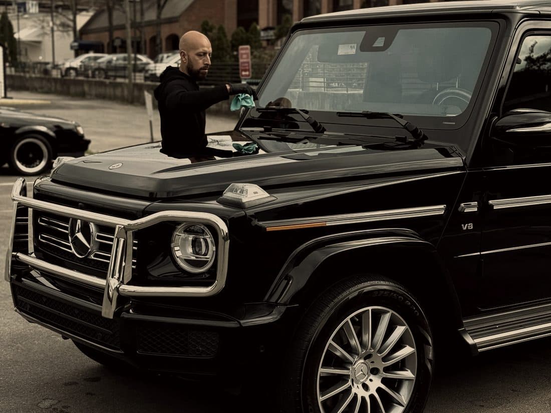 Detailer working on a black Mercedes G-Wagon on location