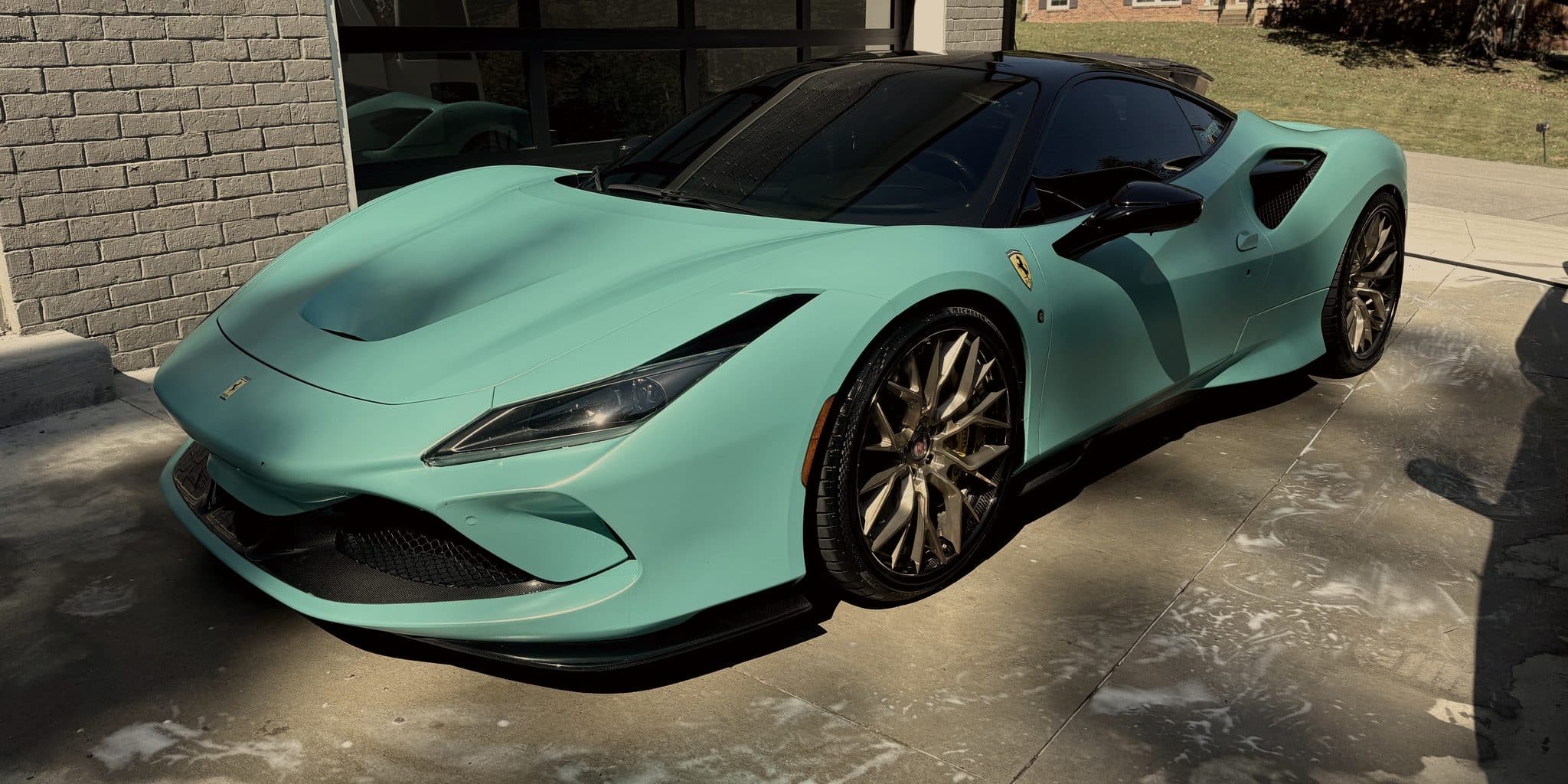 Mint green Ferrari F8 Tributo on a driveway, suds still on the concrete