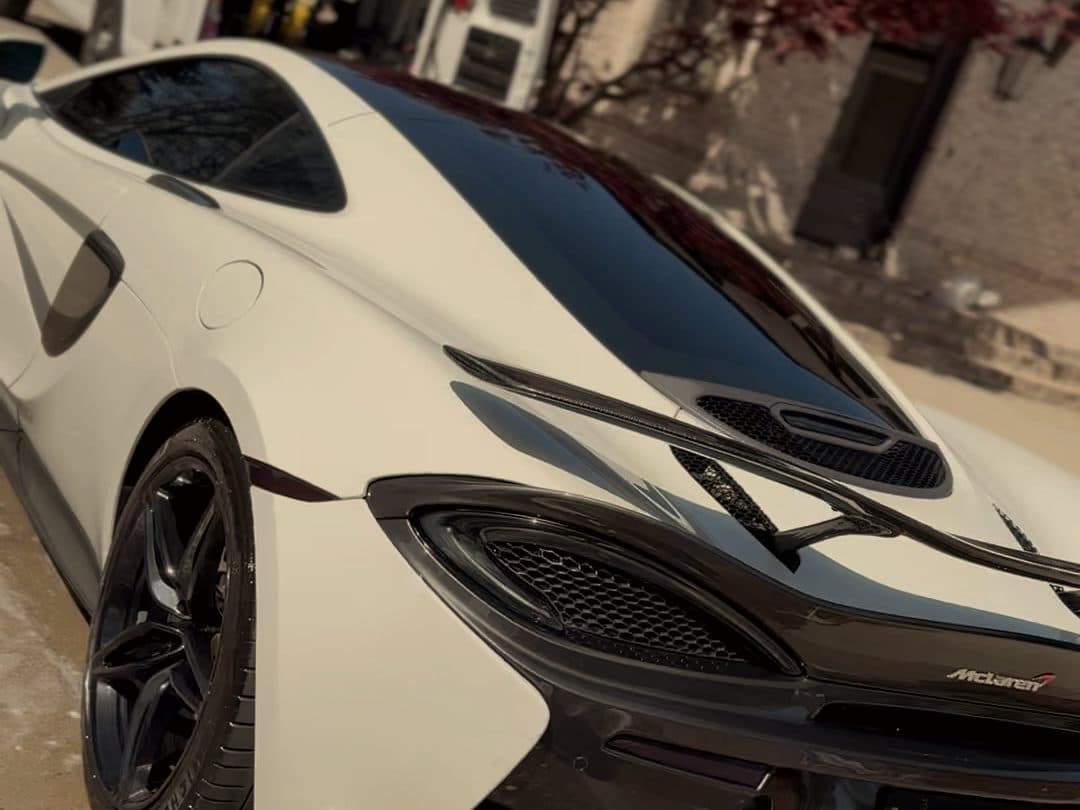 White McLaren 570S on a driveway with the work van parked behind it