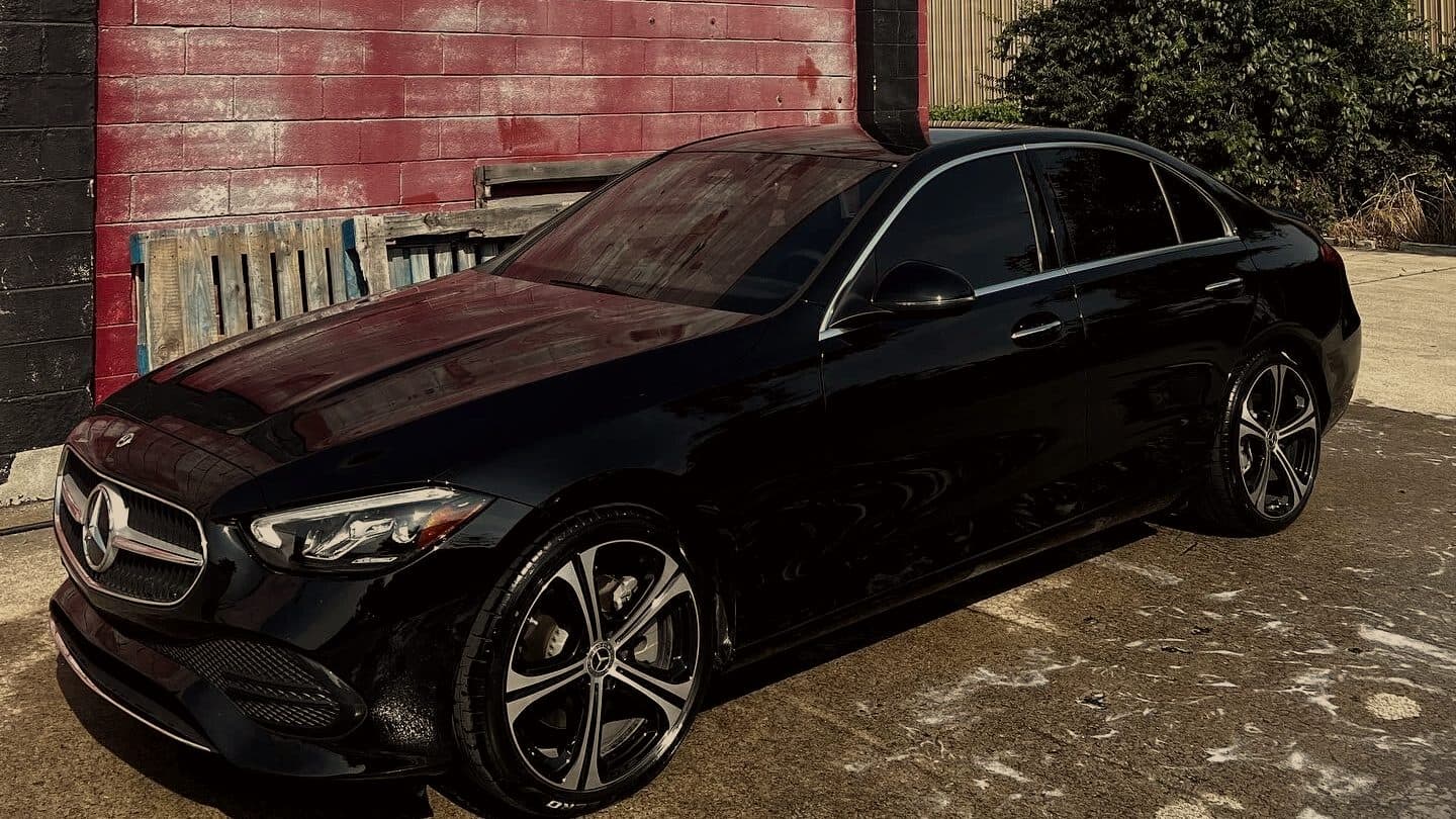 Black Mercedes sedan parked against a painted red brick wall