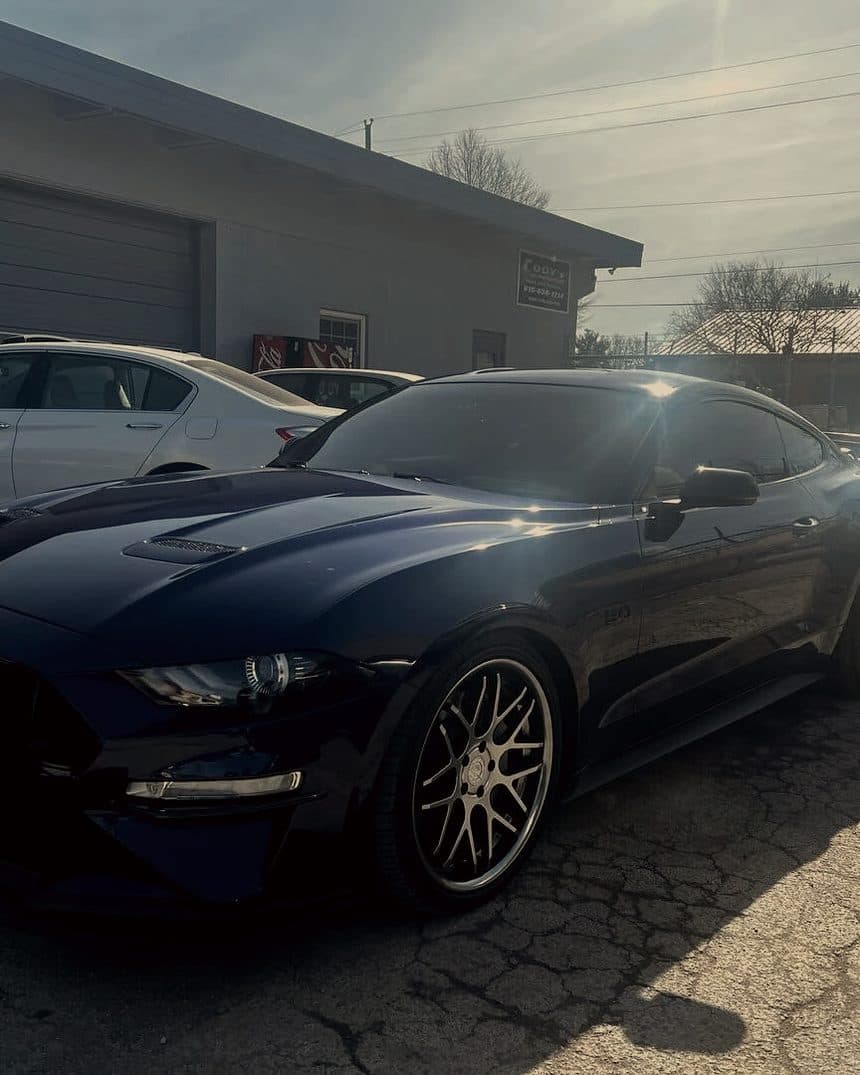 Dark blue Ford Mustang parked outside a garage