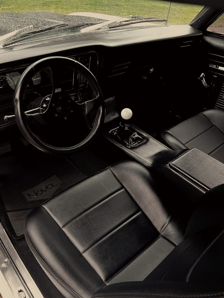 Front cabin of a Chevrolet Nova with black seats and a manual shifter
