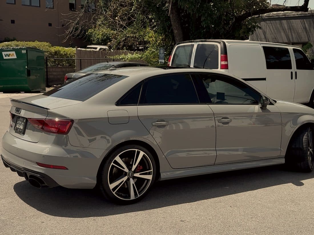 Nardo grey Audi RS3 from the rear quarter, work van parked behind it
