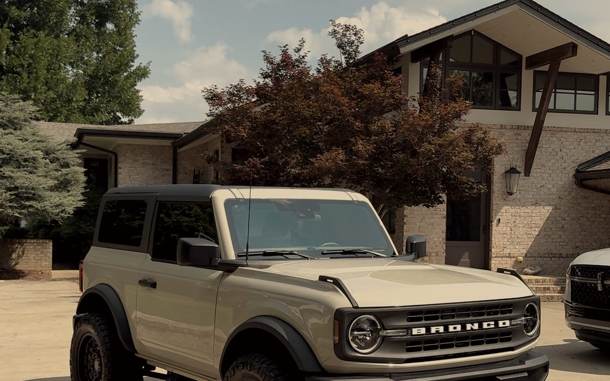 Desert tan Ford Bronco parked outside a house